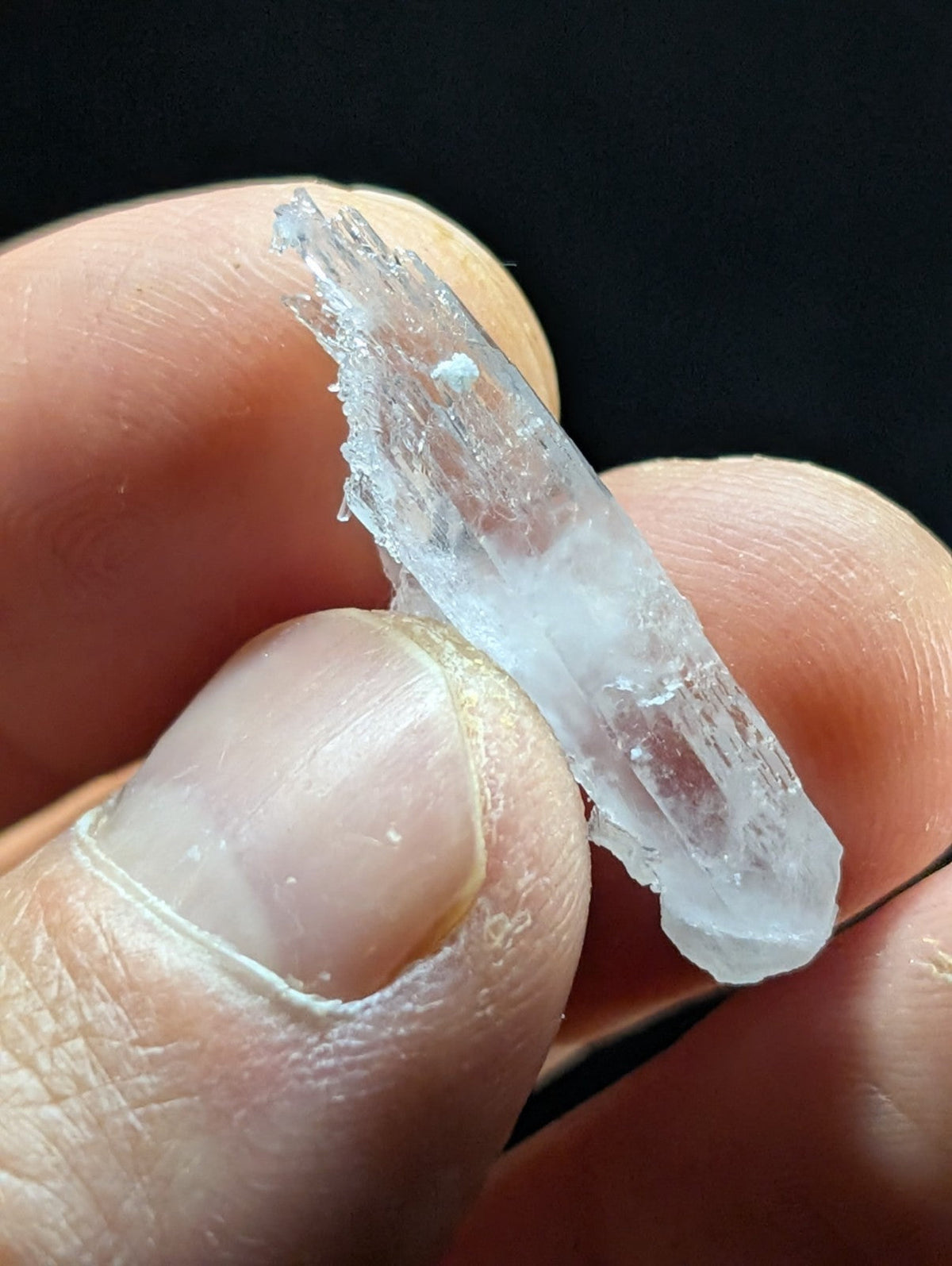 A translucent, clear quartz crystal with a jagged, natural edge and subtle internal striations.