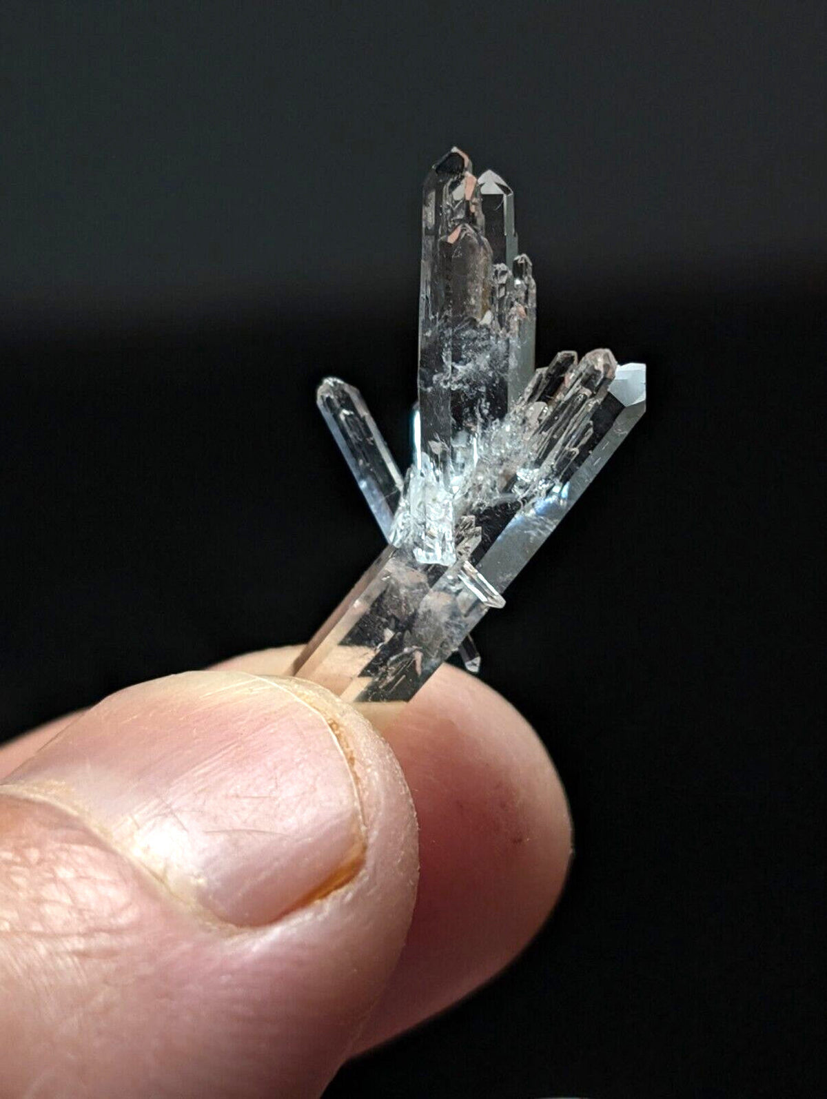 A clear, translucent quartz crystal cluster with sharp, pointed facets and a natural branching structure.