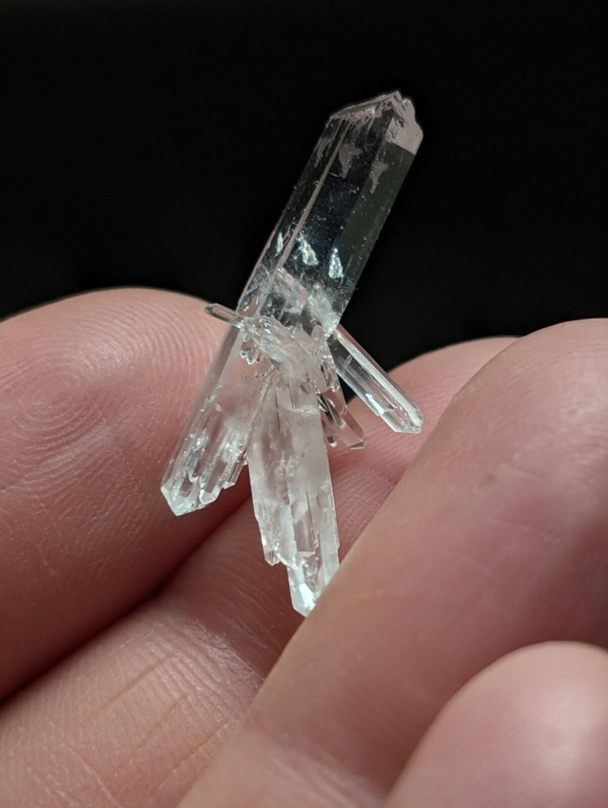 A clear, transparent quartz crystal cluster with multiple pointed facets and a natural, jagged growth pattern.
