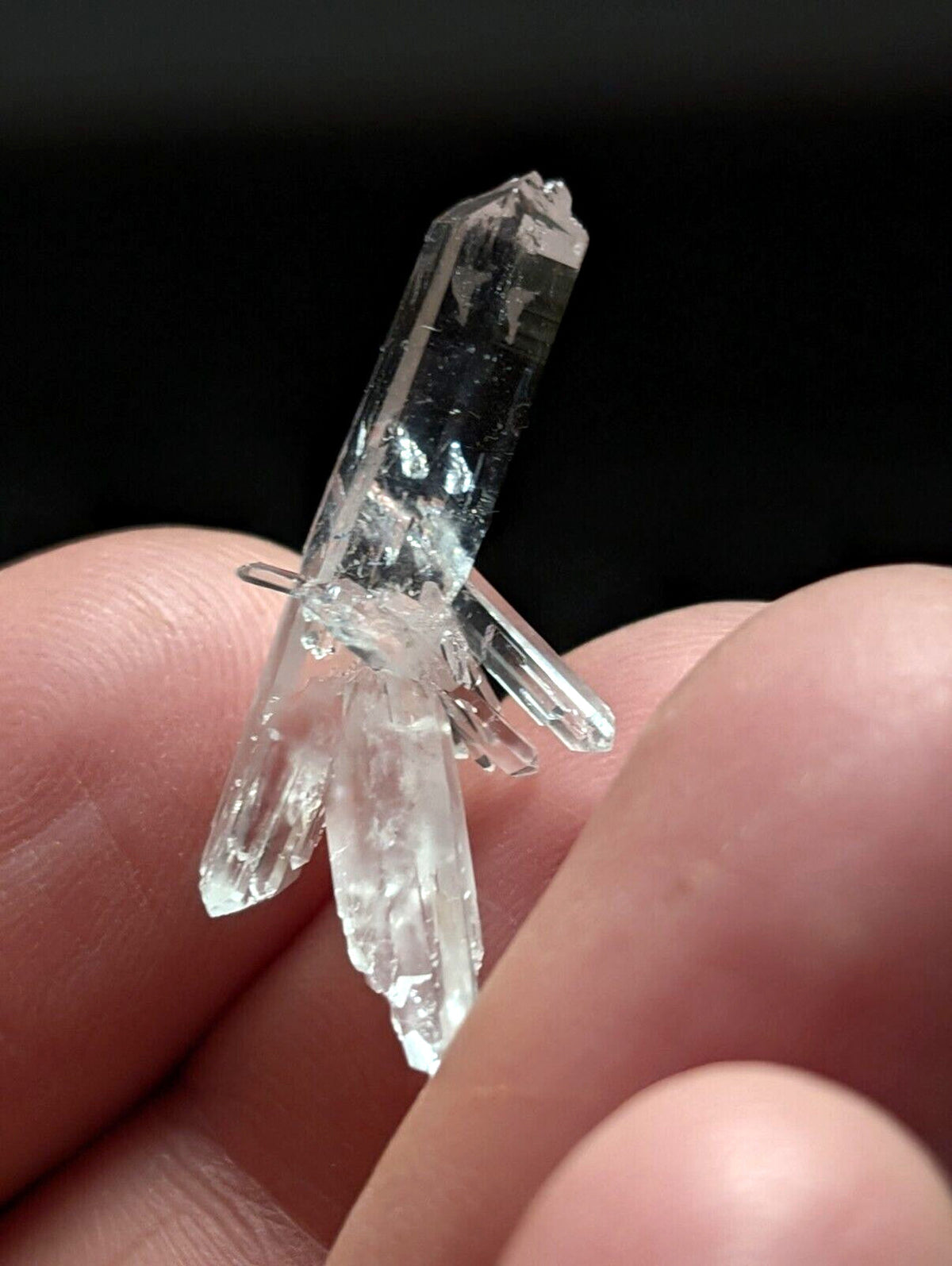 A clear, transparent quartz crystal cluster with multiple pointed facets and a natural, jagged growth pattern.