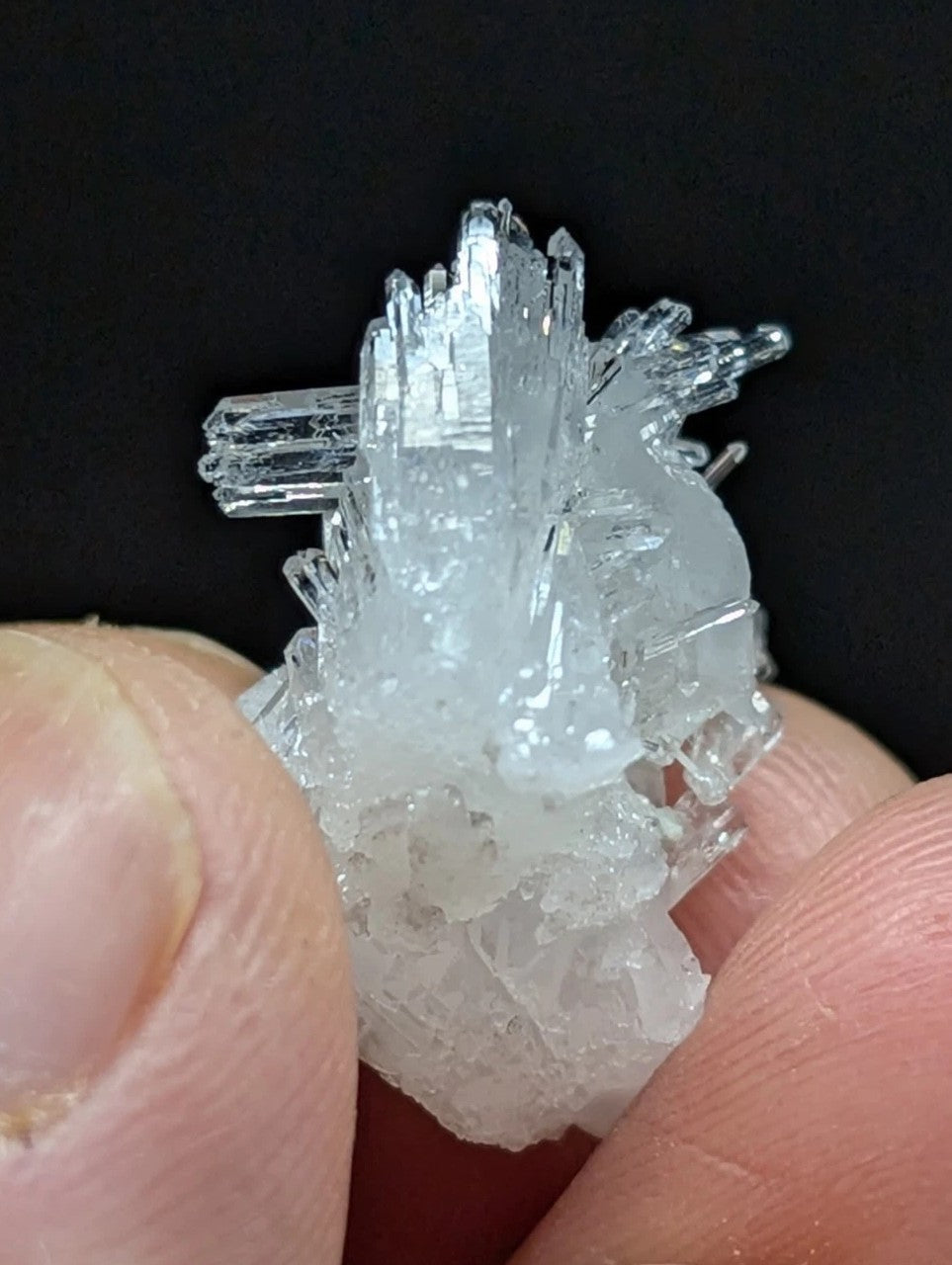 A translucent, crystalline mineral specimen with sharp, jagged facets and a cluster of clear to slightly cloudy crystals forming an intricate, natural geometric structure.