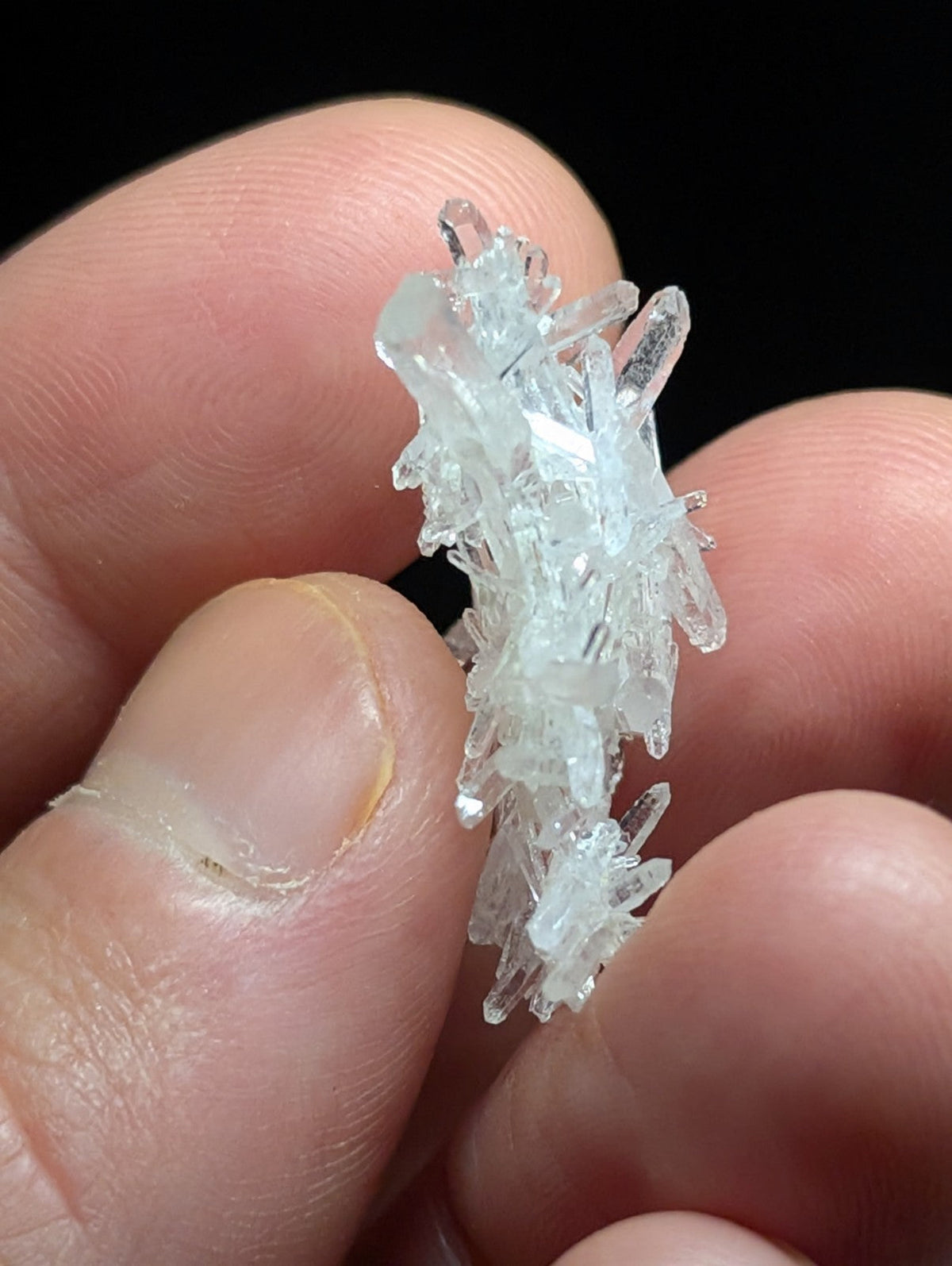 A translucent, clear quartz crystal cluster with sharp, interlocking facets and a delicate, branching structure.