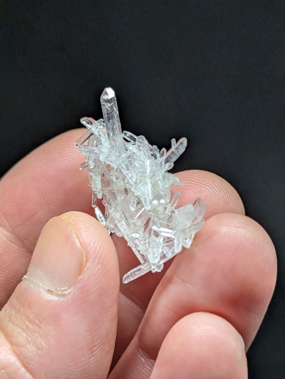 A clear, translucent quartz crystal cluster with sharp, jagged edges and multiple pointed prisms.