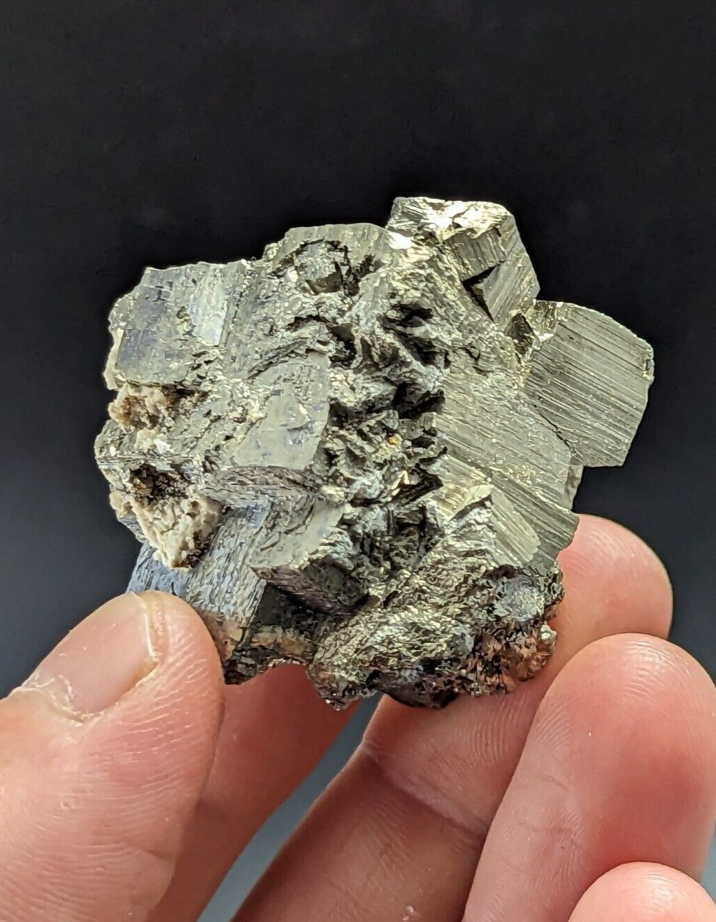 A rough, metallic greenish-gray mineral specimen with distinct crystalline facets and a textured surface.