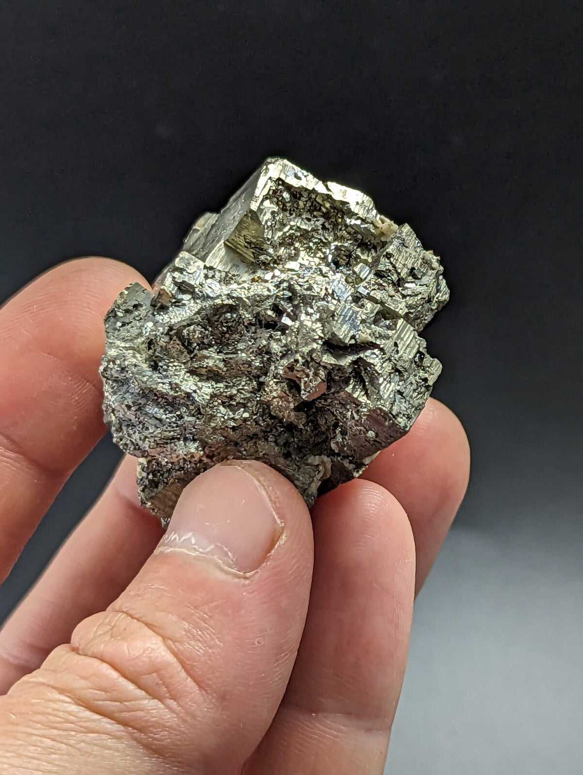 A metallic, silver-colored pyrite mineral specimen with a rough, jagged surface and visible crystalline facets.
