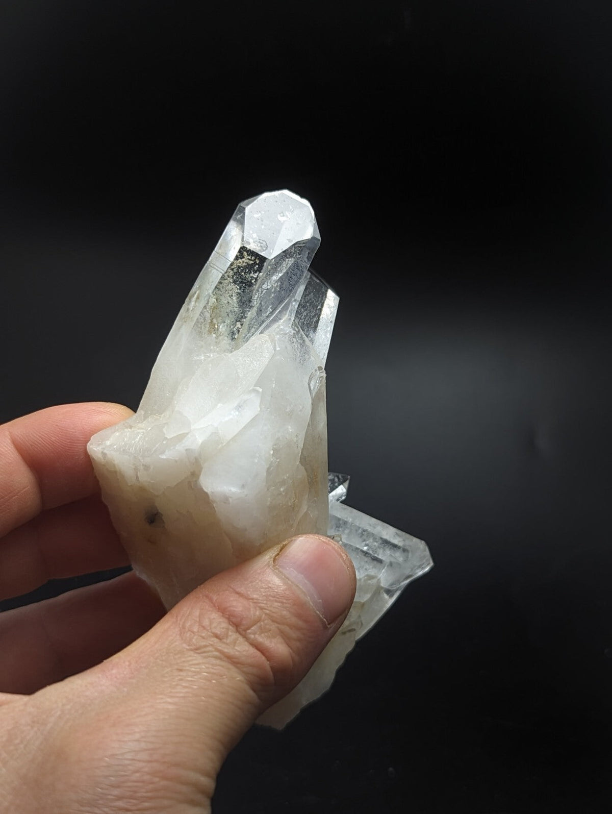 A translucent, clear quartz crystal cluster with a slightly milky base and sharp, faceted points.