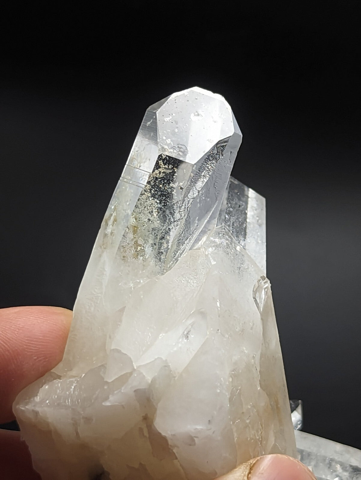 A clear, translucent quartz crystal cluster with a prominent pointed tip and layered facets.
