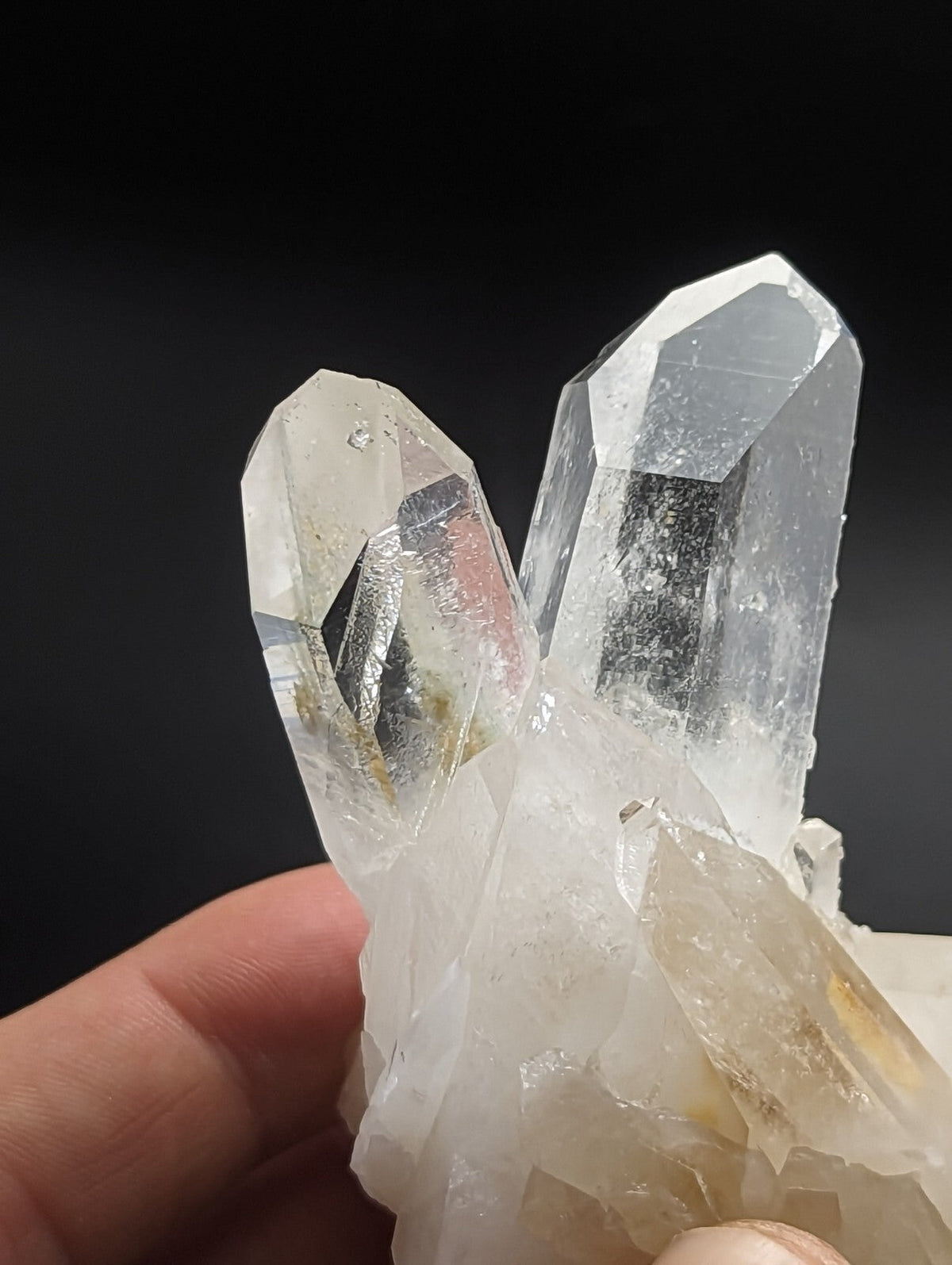 A clear, translucent quartz crystal cluster with sharp, faceted points and a slightly cloudy base.