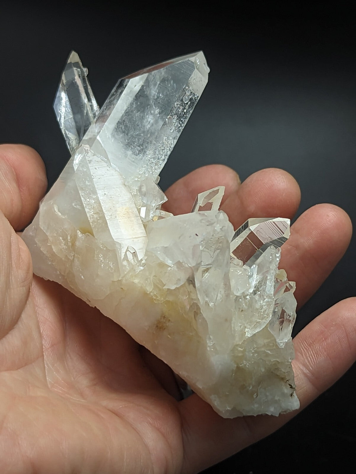 A translucent, clear quartz crystal cluster with sharp facets and a slightly milky base.