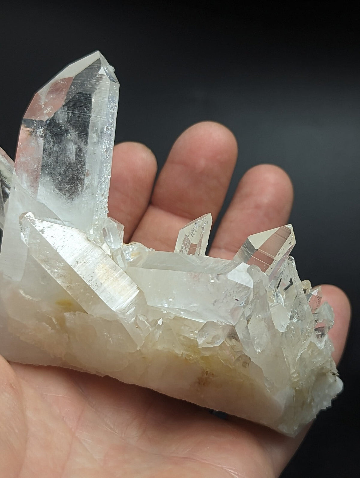 A translucent, clear quartz crystal cluster with sharp facets and a slightly milky base.