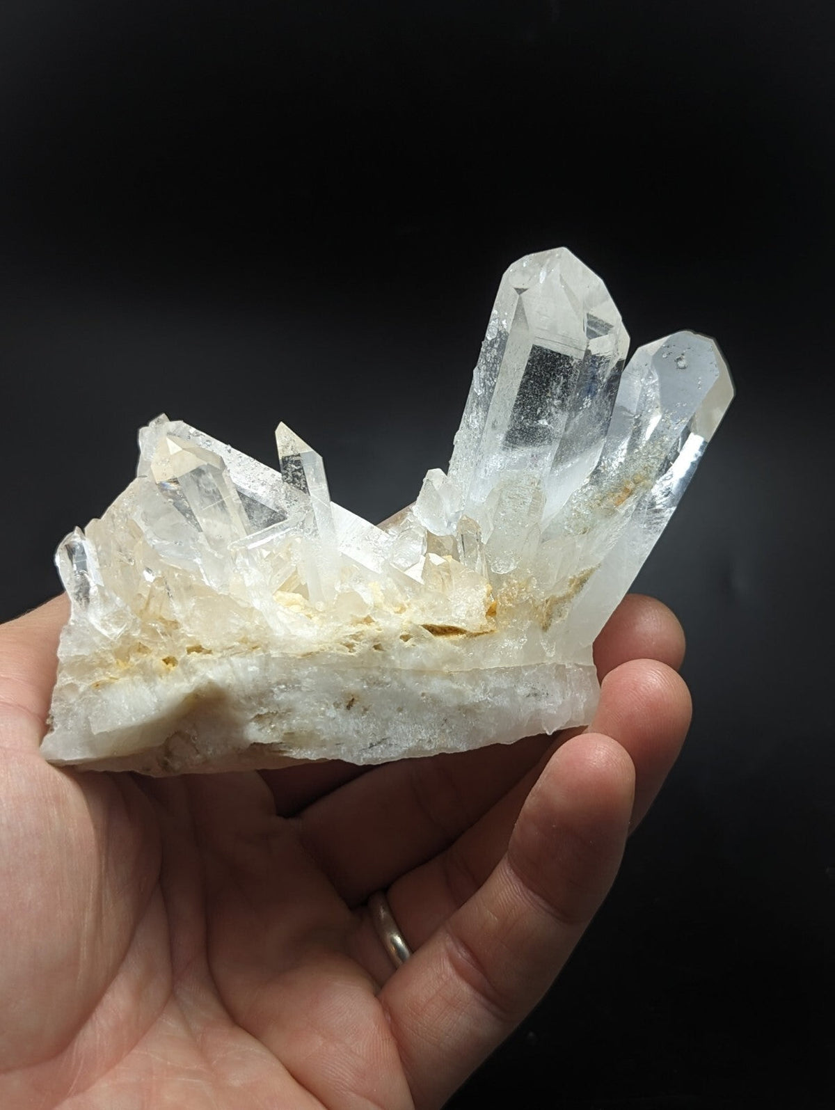 A translucent quartz crystal cluster with clear, pointed formations and a slightly yellowish base.