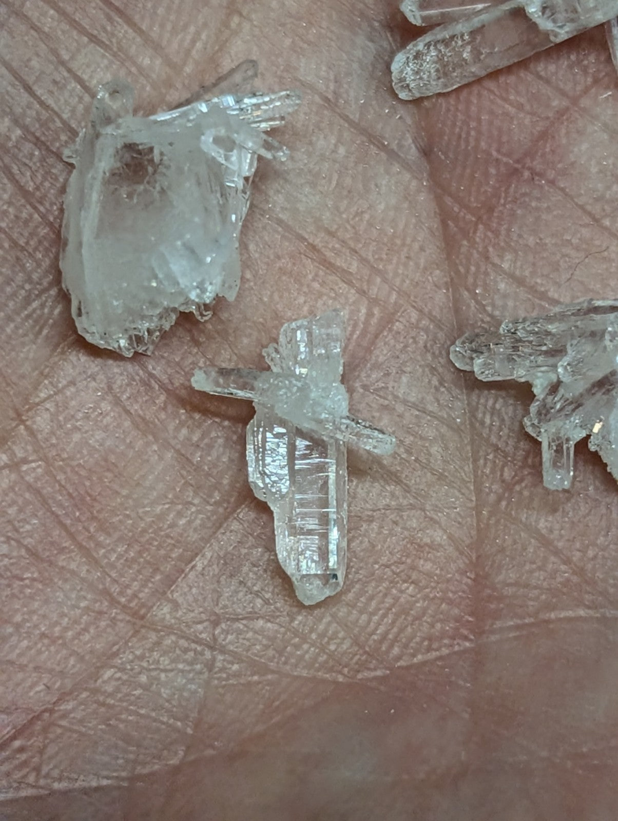 Clear quartz crystal clusters resting in an open palm.