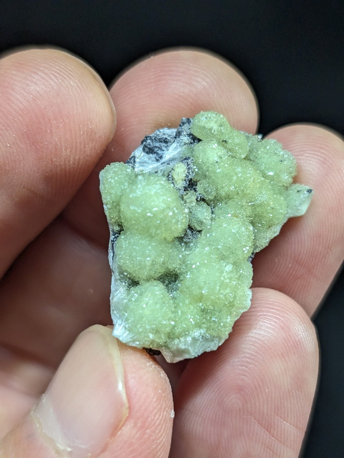 A pale green, crystalline mineral specimen with rounded, clustered formations and a translucent quality.