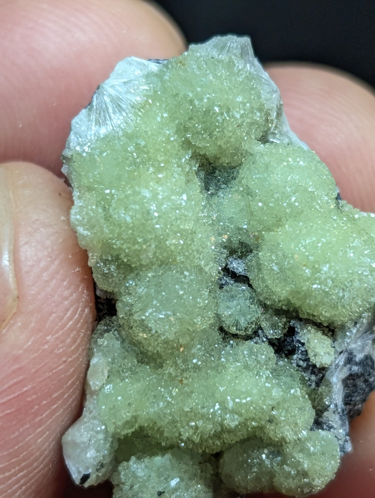 A pale green, crystalline mineral specimen with a rough, textured surface and translucent facets.
