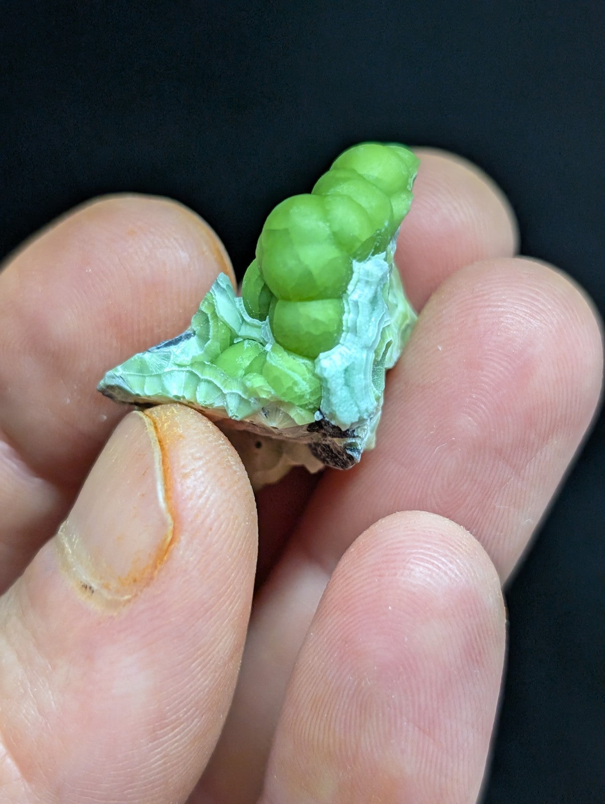 A vibrant green, geode-like mineral specimen with a faceted, spherical cluster atop a textured base.