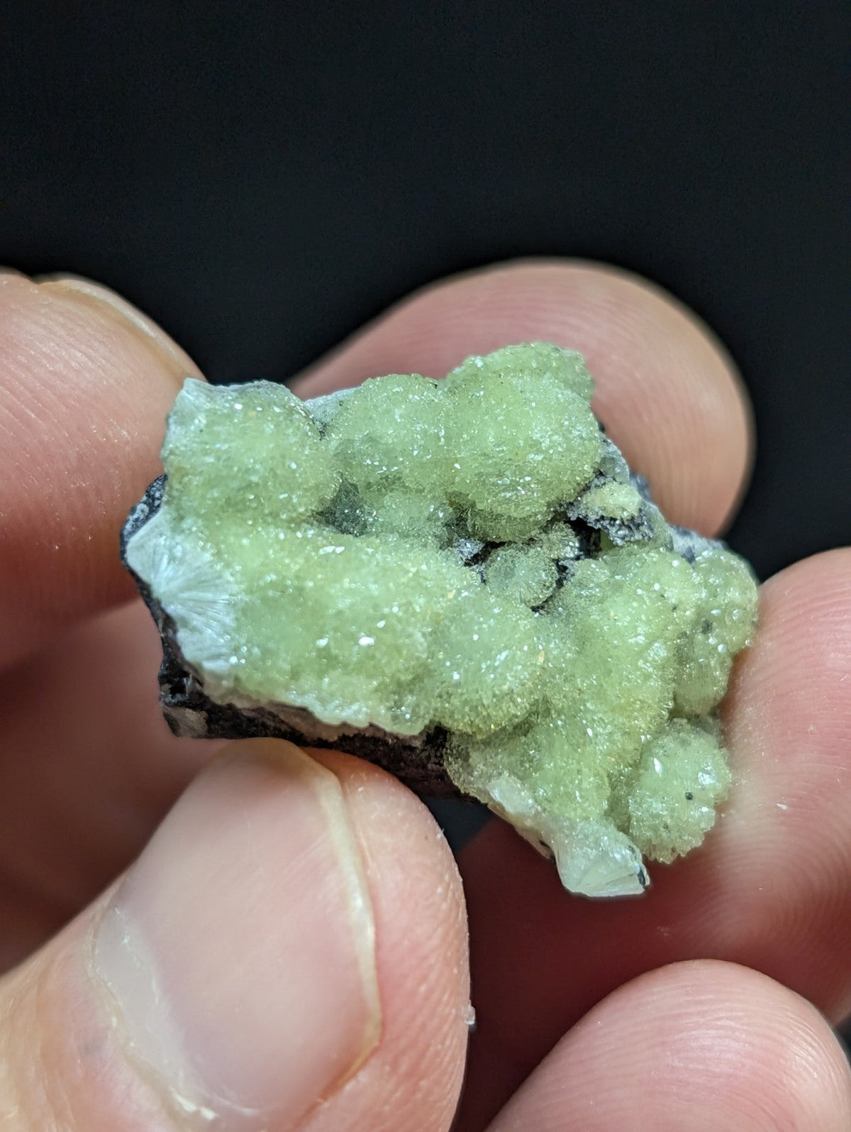 A cluster of pale green, crystalline minerals with a rough, textured surface and translucent quality.