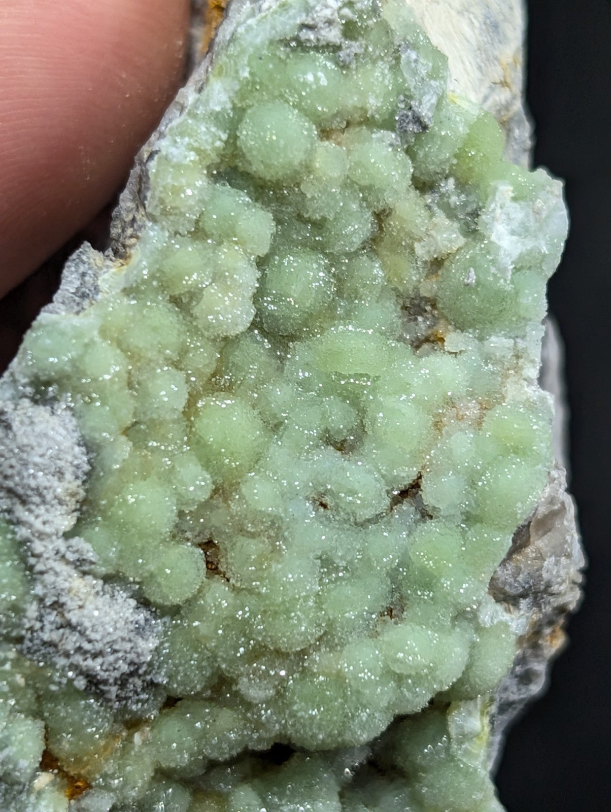 A cluster of translucent, light green crystalline formations with a sparkling, glassy texture.