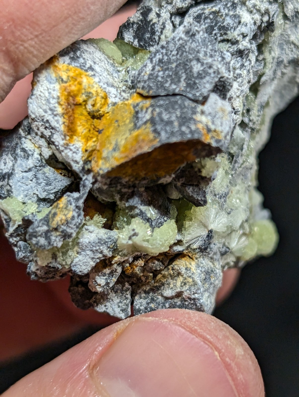 A rugged, naturally occurring mineral specimen featuring a striking contrast of grayish rock matrix with vibrant yellow and pale green crystalline formations.