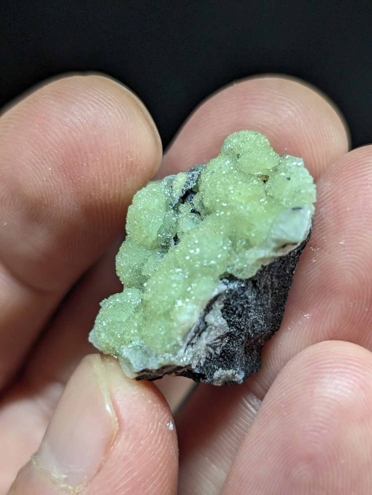 A vibrant green, crystalline mineral specimen with a rough, textured surface and dark matrix base.