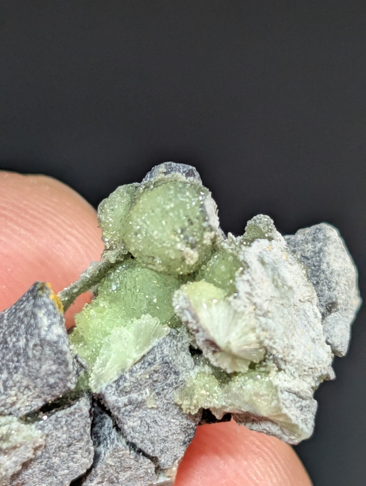 A cluster of translucent green crystals with a powdery, grayish matrix.