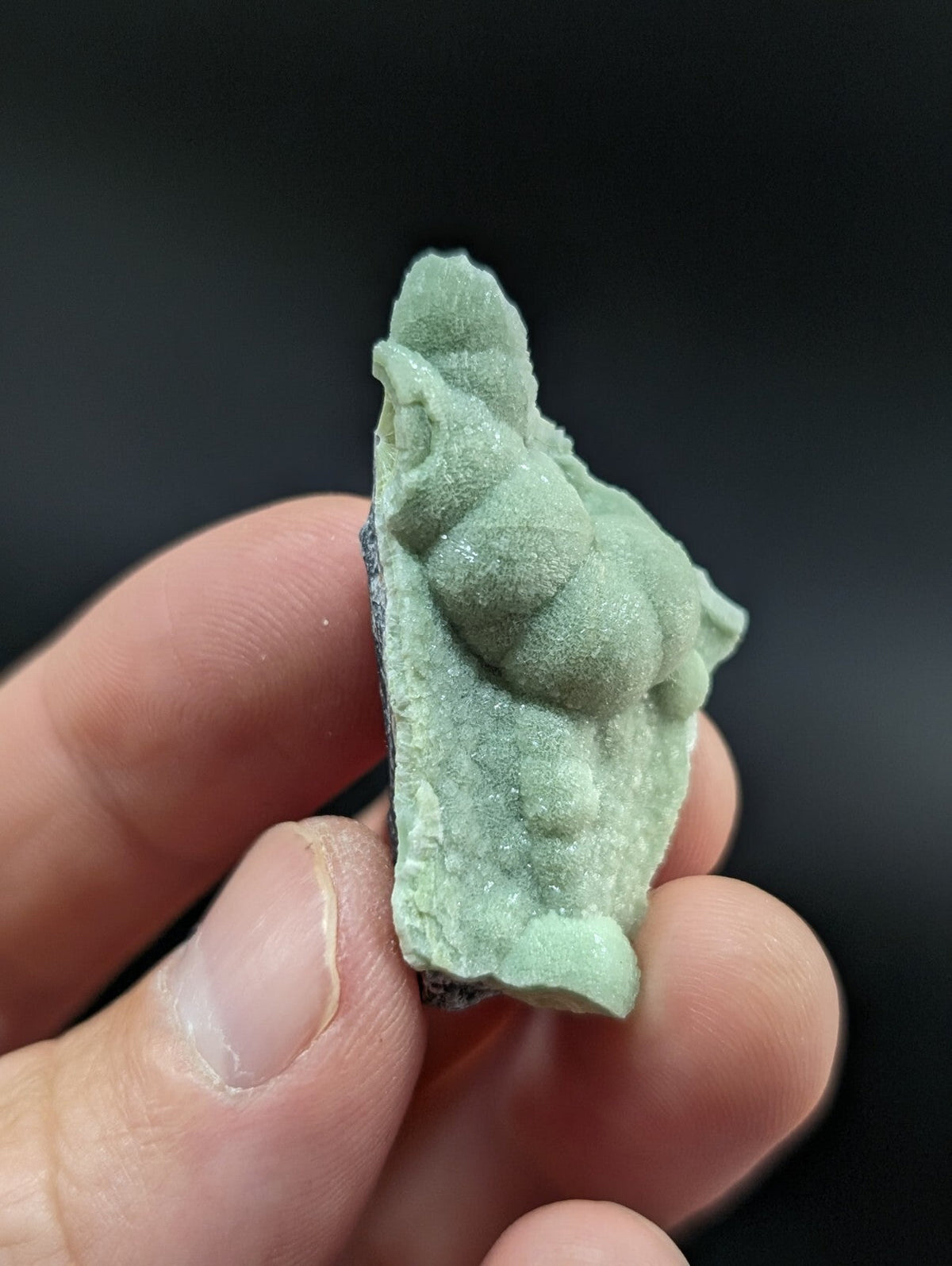 A pale green, textured mineral specimen with a rough, uneven surface and natural crystalline formations.