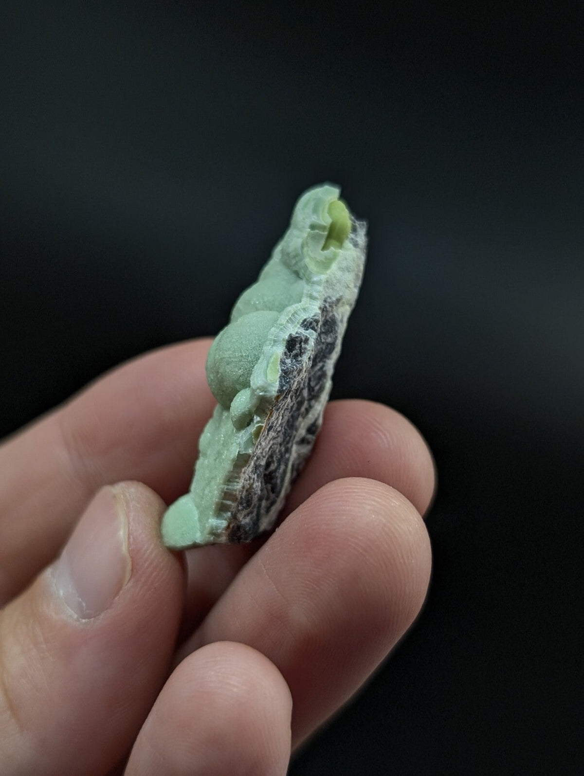 A pale green, textured mineral specimen with a rough, layered surface and subtle crystalline formations.