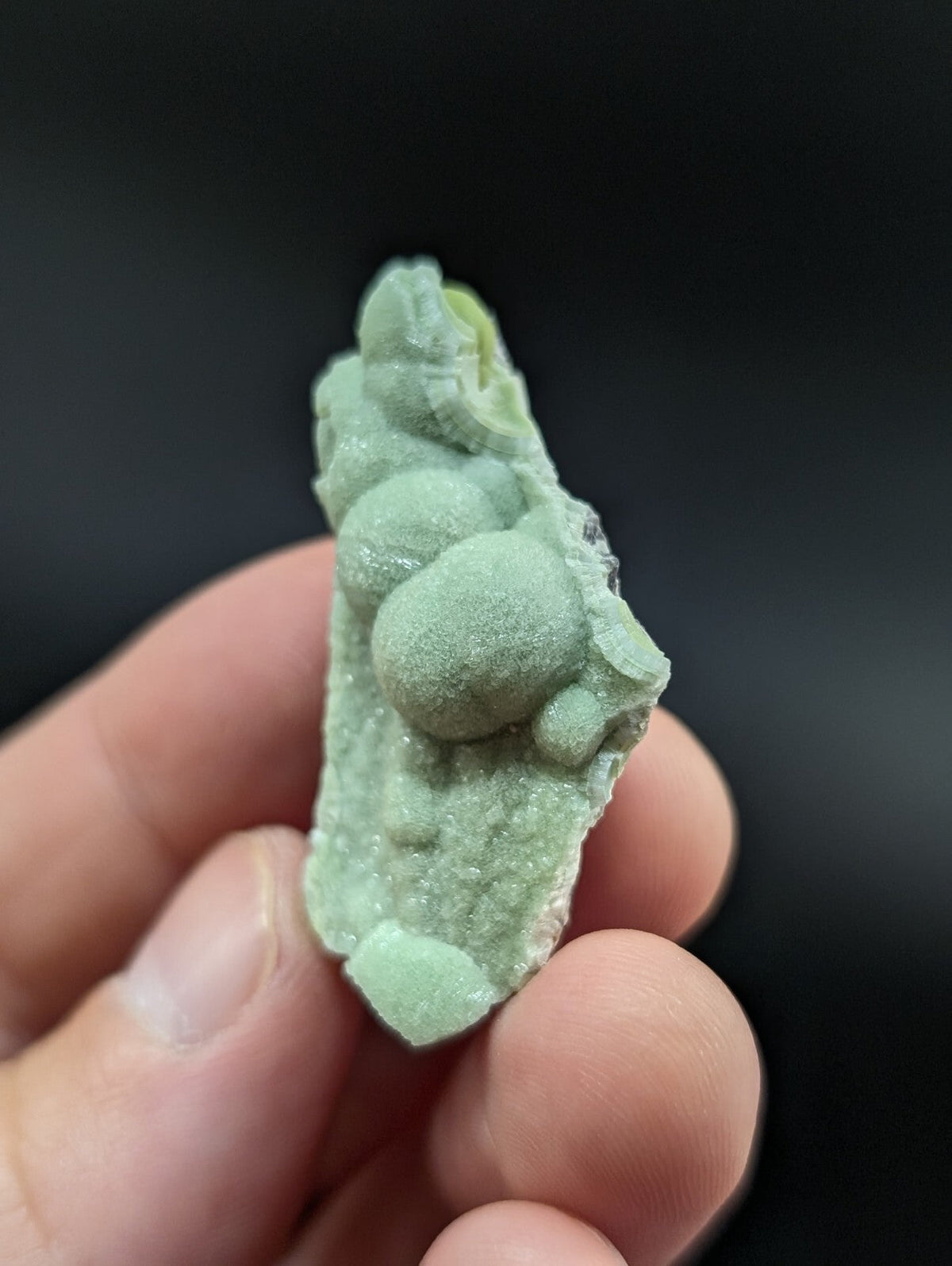 A pale green, textured mineral specimen with rounded nodules and a rough, crystalline surface.