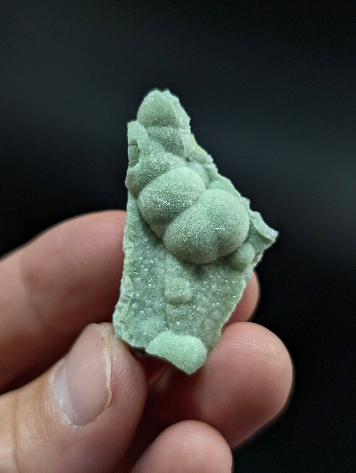 A light green, textured mineral specimen with rounded nodules and a rough, crystalline surface.