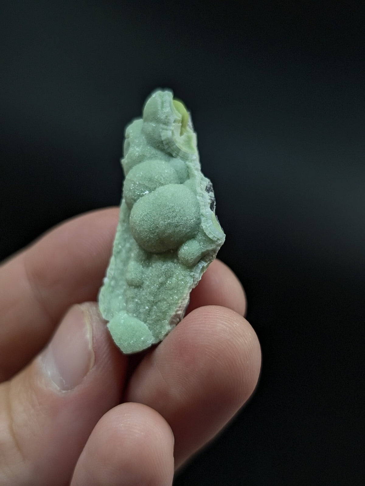 A pale green, crystalline mineral specimen with rounded nodules and a rough, textured surface.