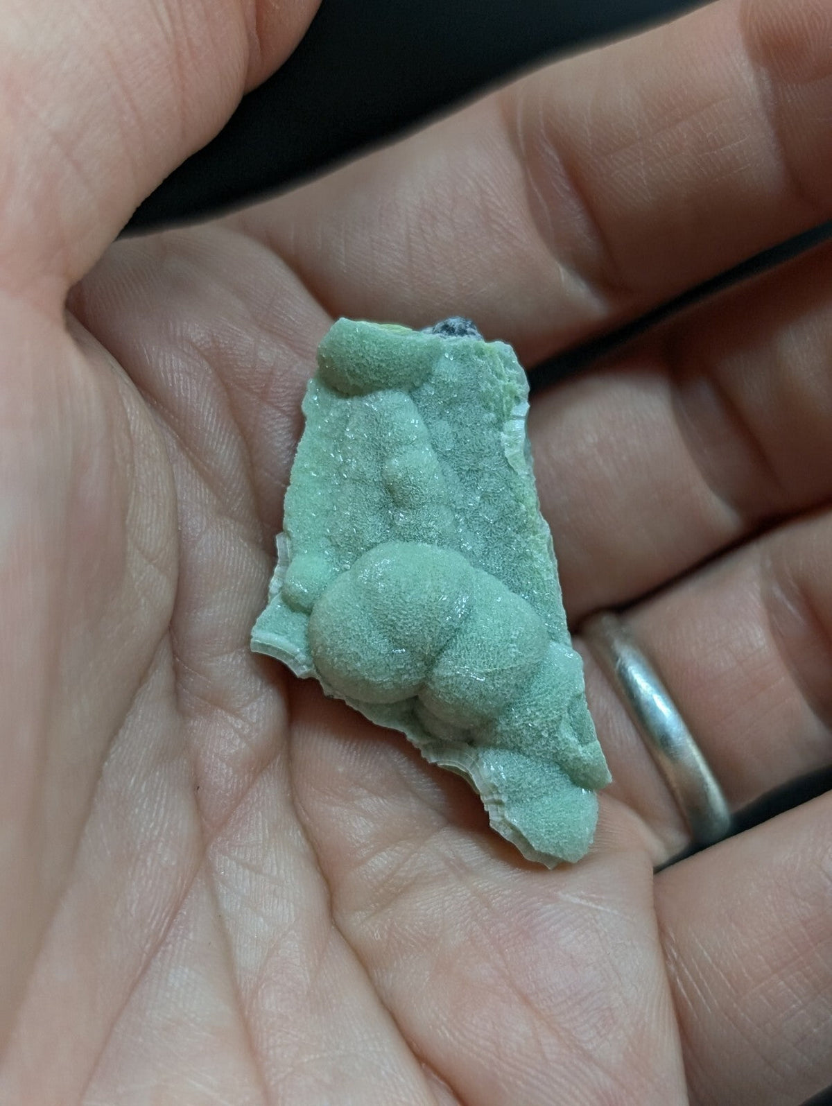 A pale green, textured mineral specimen with a rough, irregular surface and small rounded protrusions.