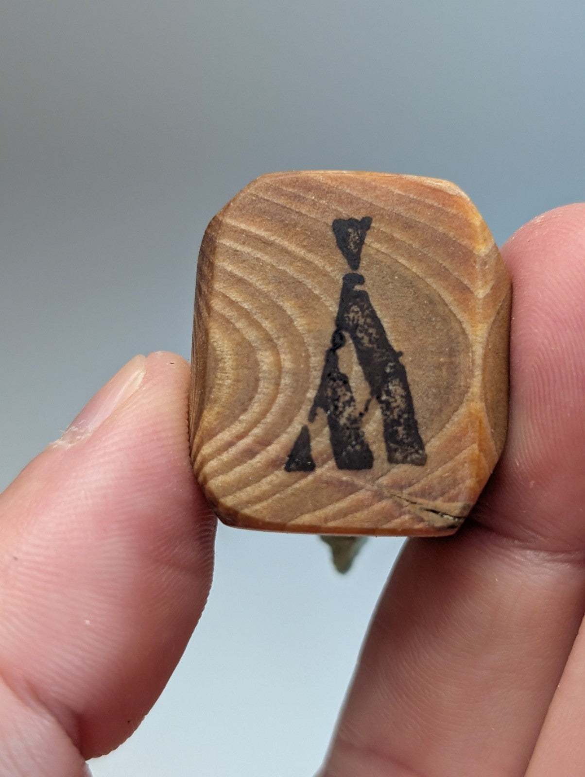 A hand holds a square wooden carving with black ink silhouette on handmade wood mount from Garland County Arkansas