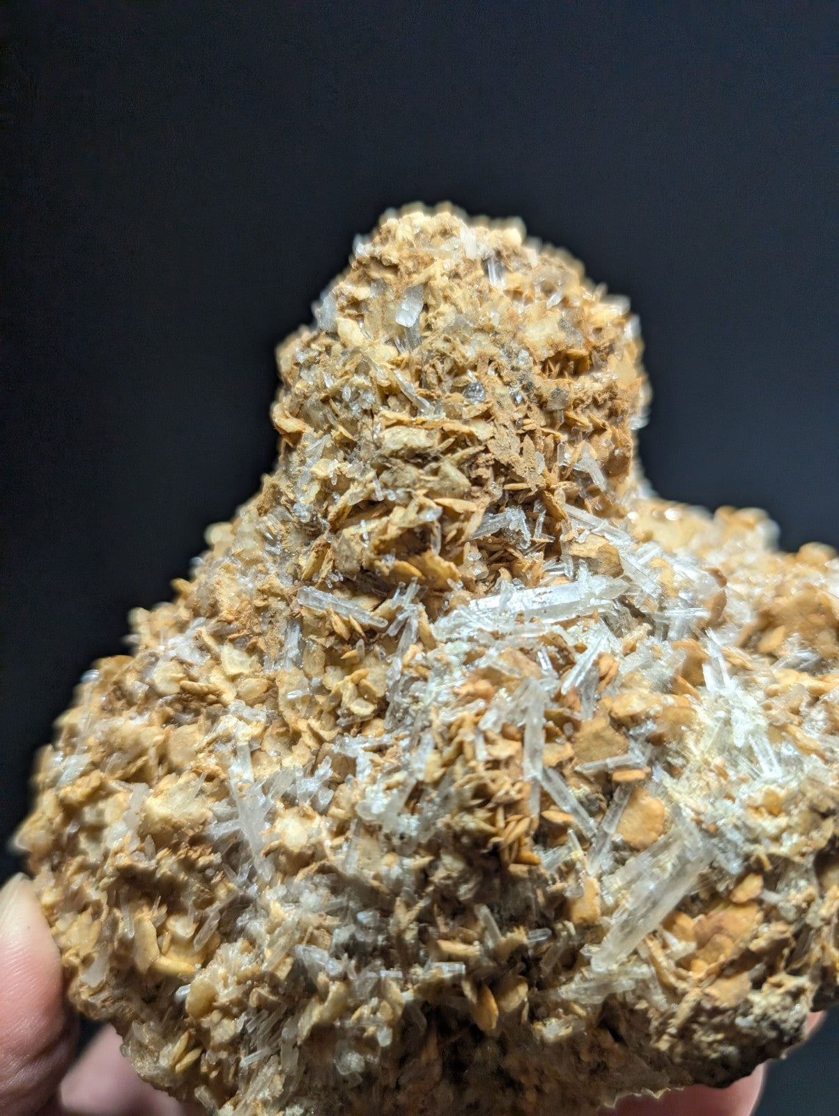 A rugged, earthy-toned mineral specimen featuring translucent quartz crystals emerging from a textured matrix of brownish rock.
