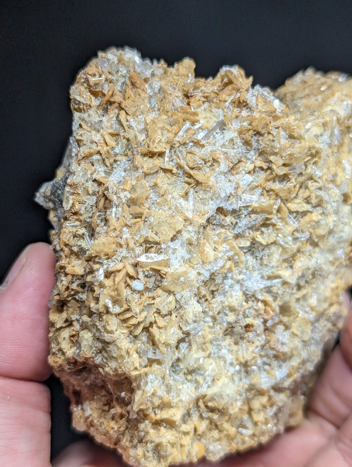 A rough, irregularly shaped mineral specimen with a textured surface featuring translucent white crystals embedded in a golden-brown matrix.