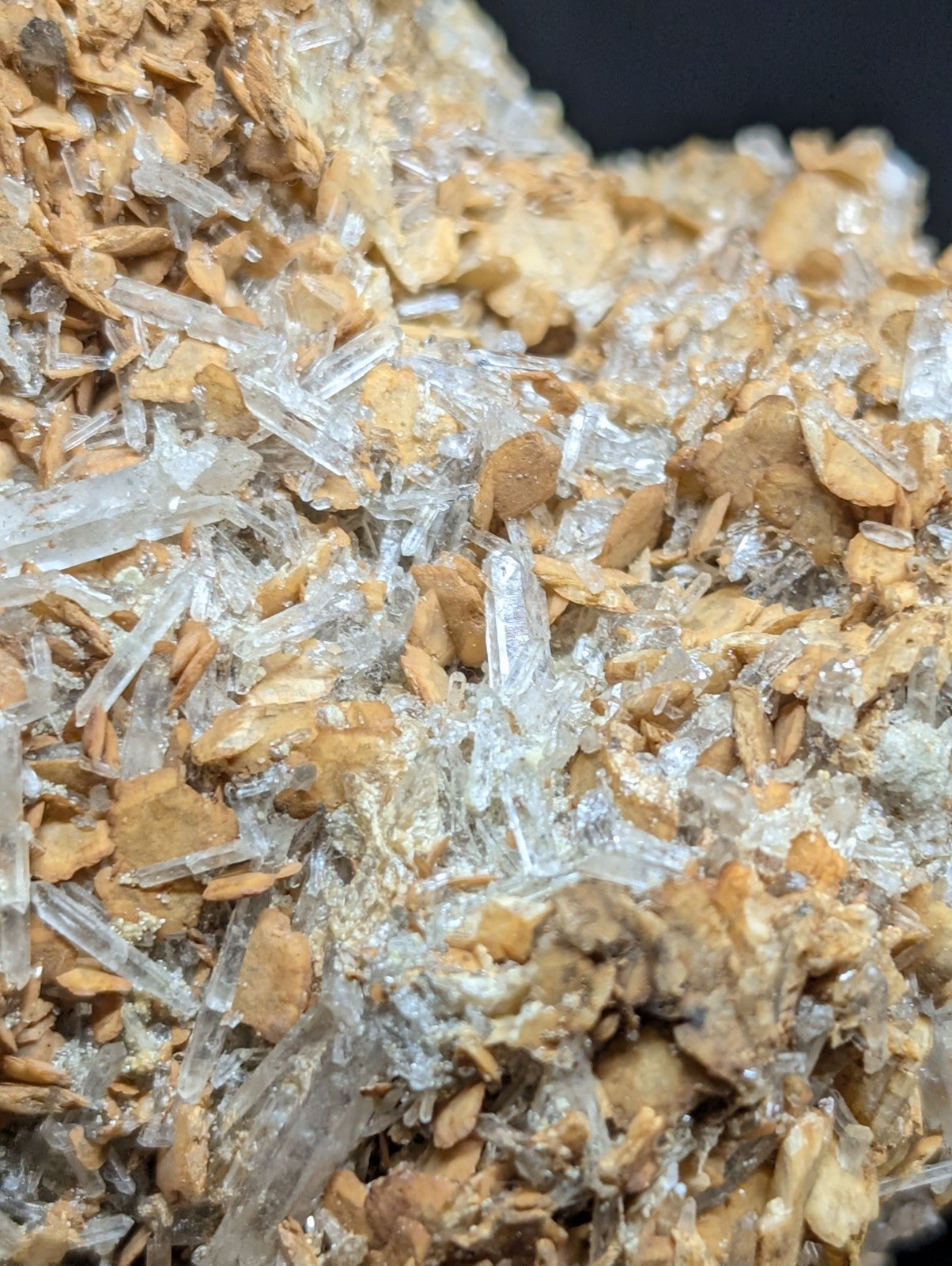 A cluster of transparent quartz crystals growing from a brownish, earthy matrix.