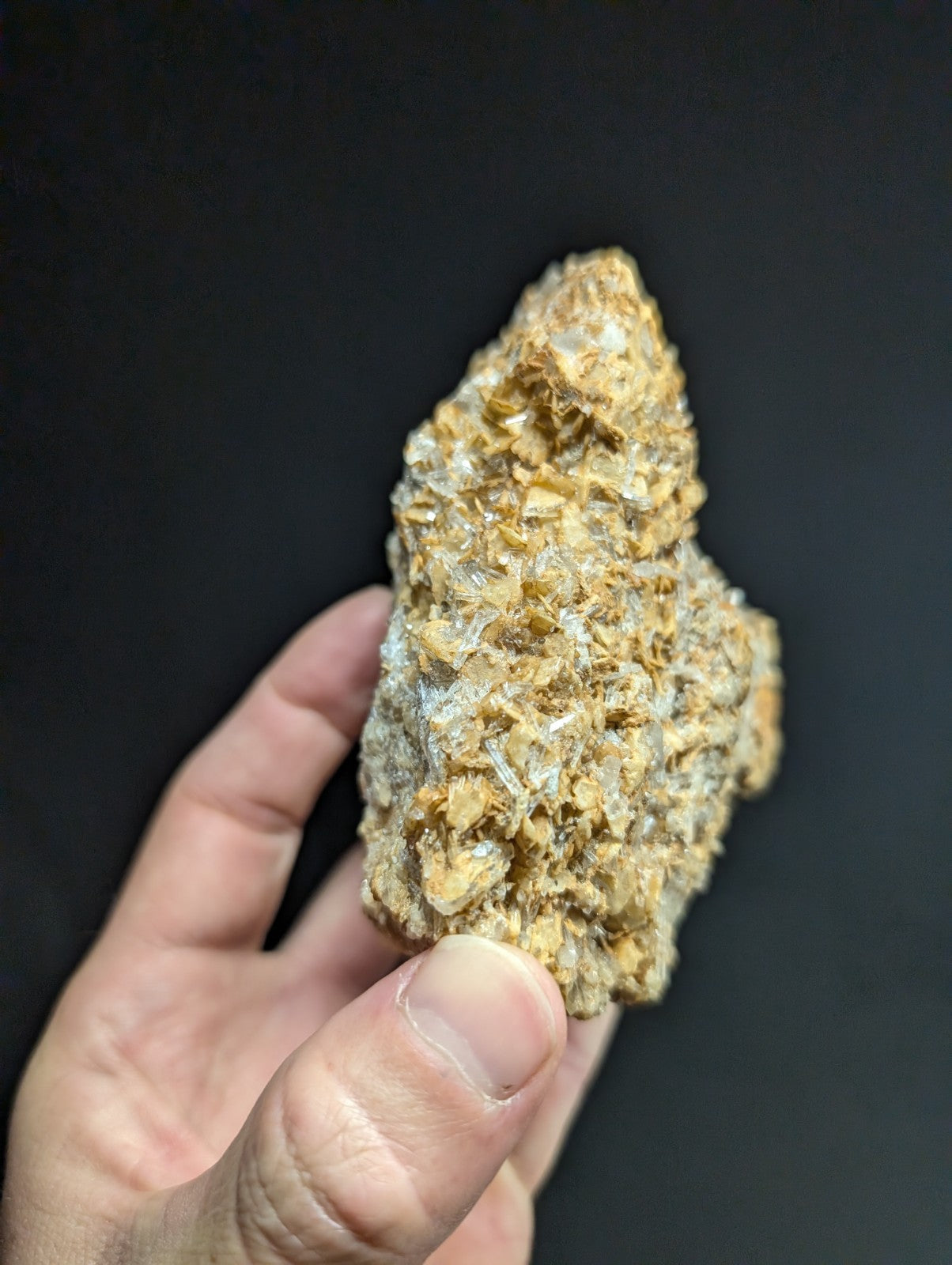 A rough, irregularly shaped mineral specimen with a textured surface featuring golden-yellow and translucent crystalline formations.