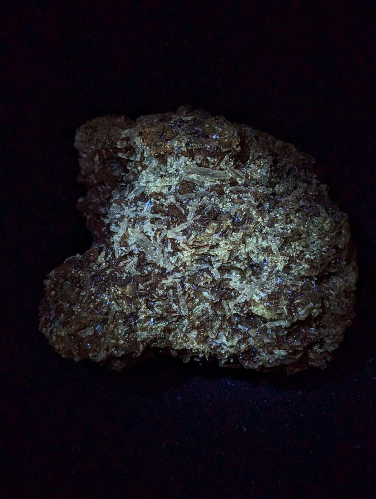 A rough, irregularly shaped mineral specimen with a dark brown base and prominent translucent, crystalline formations that shimmer with hints of metallic sheen.