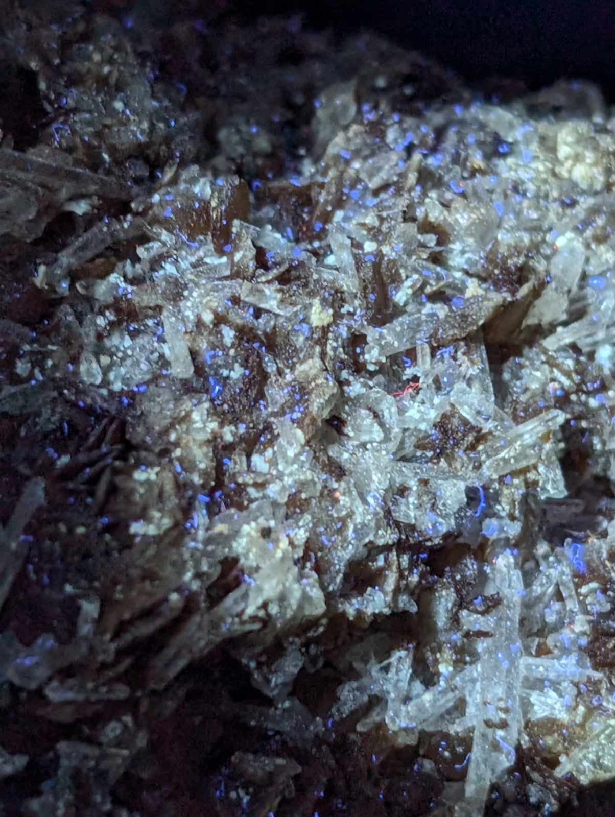 A cluster of translucent, crystalline minerals with a mix of white and brown hues, featuring sharp, jagged edges and glowing blue highlights.