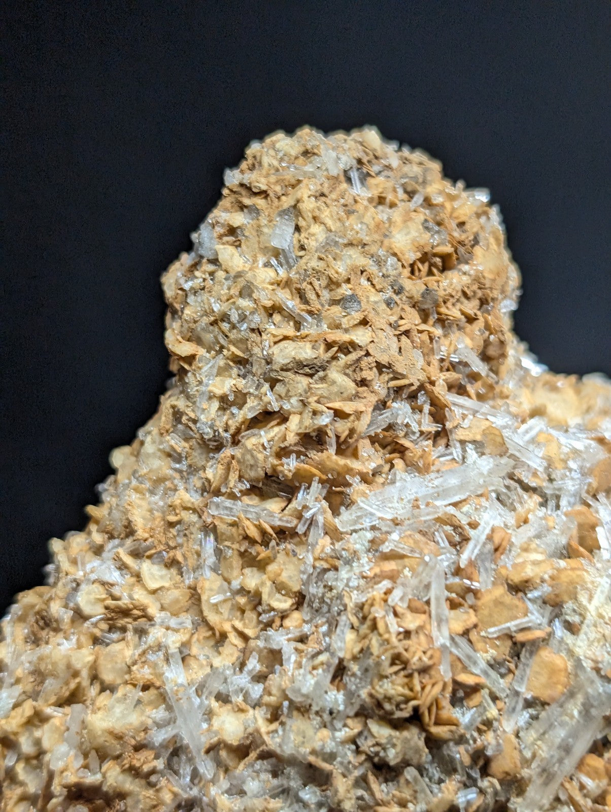 A cluster of translucent quartz crystals growing from a textured, earthy-brown mineral matrix.