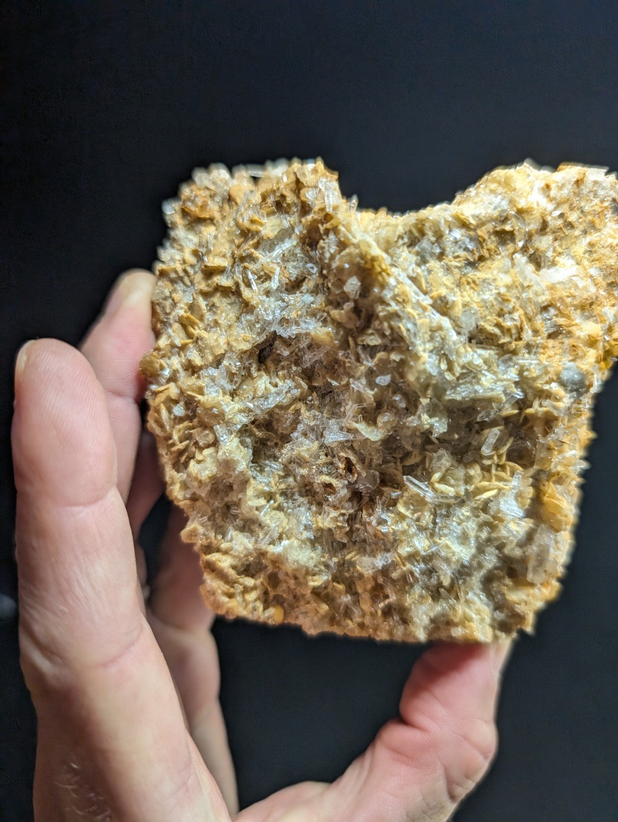 A textured, golden-brown mineral specimen with crystalline formations and a rough, uneven surface.