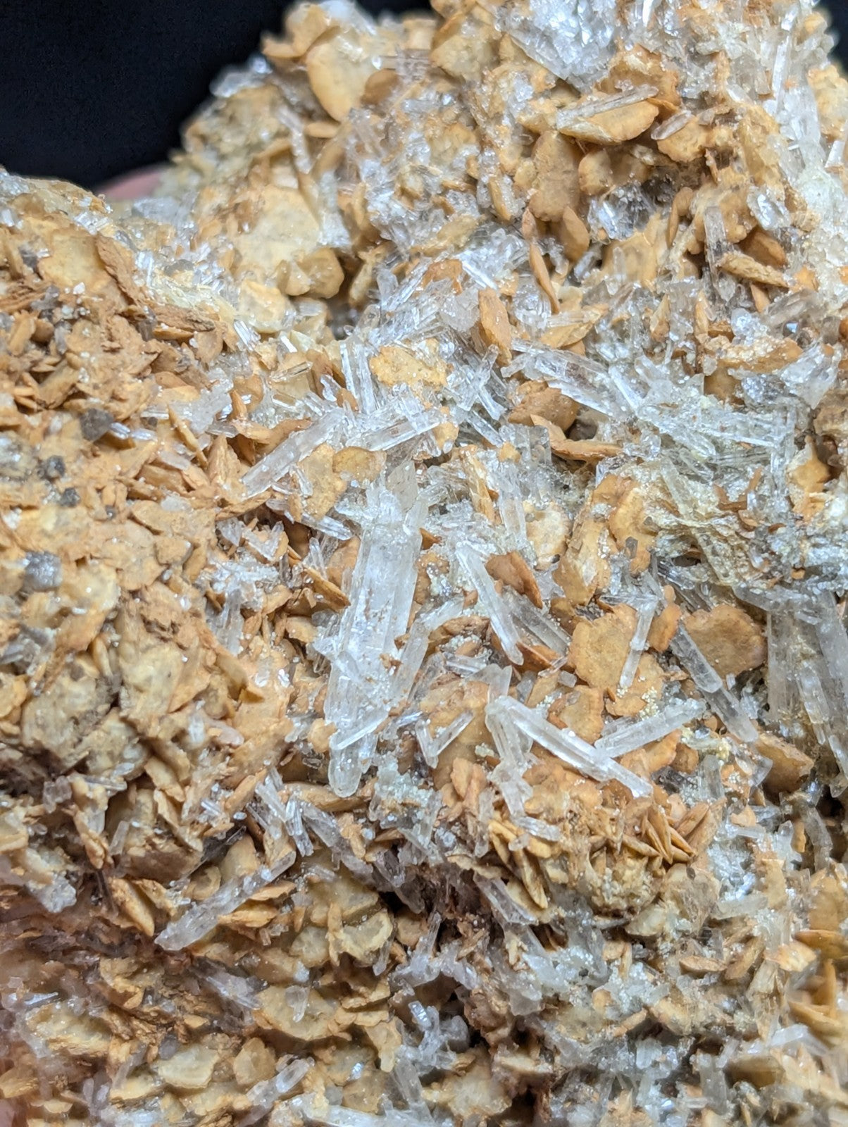 A cluster of translucent, clear quartz crystals growing from a textured, earthy brown rock matrix.