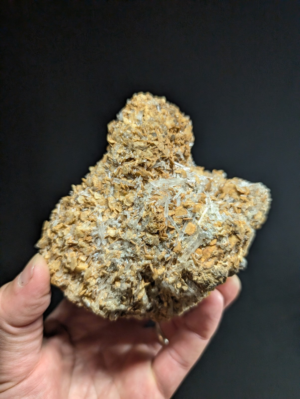 A rough, irregularly shaped mineral specimen with a textured surface featuring golden-brown matrix and translucent white crystalline formations.
