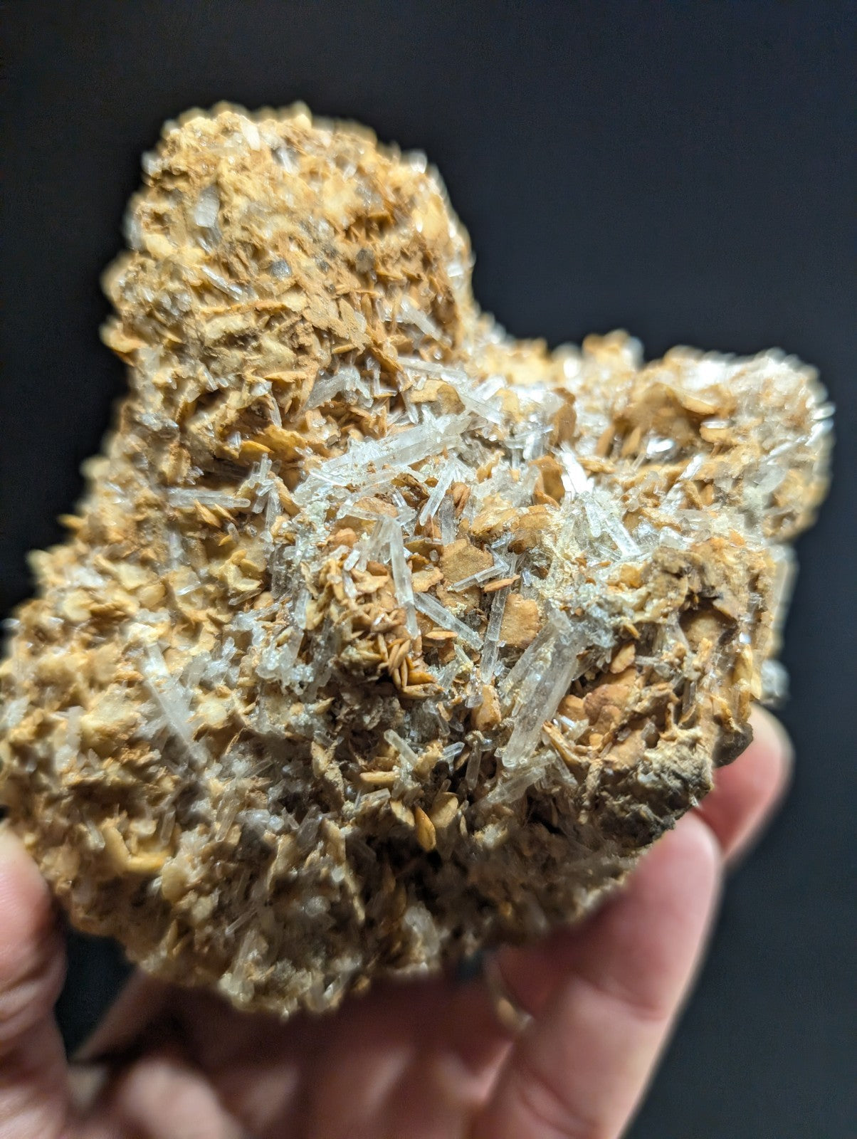 A rugged, earthy-toned mineral specimen featuring translucent quartz crystals growing from a textured matrix of brownish rock.