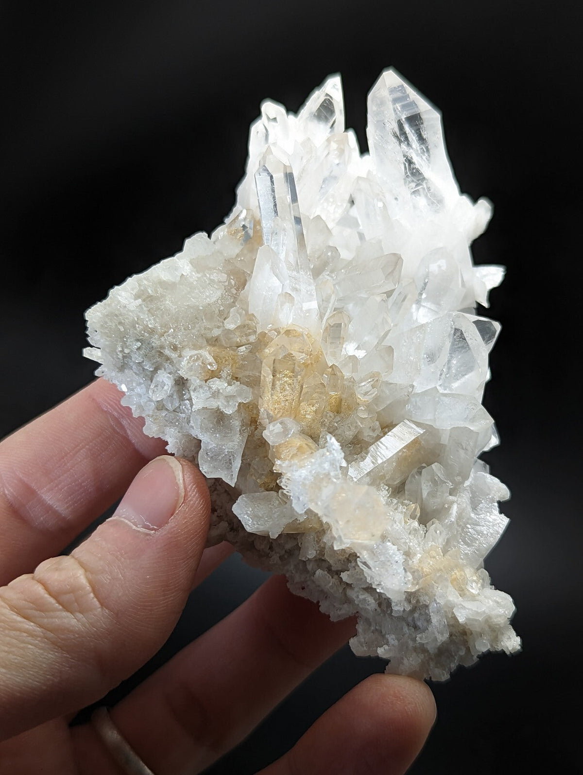 A translucent white quartz crystal cluster with sharp, pointed facets and a subtle golden hue at its base.