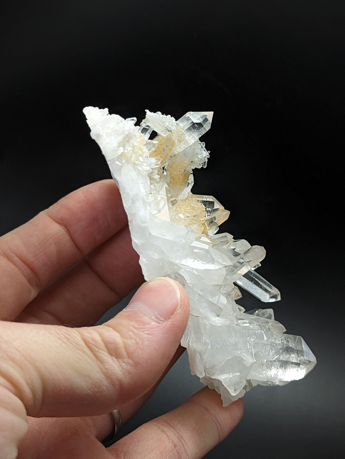 A translucent white and golden quartz crystal cluster held in a hand.