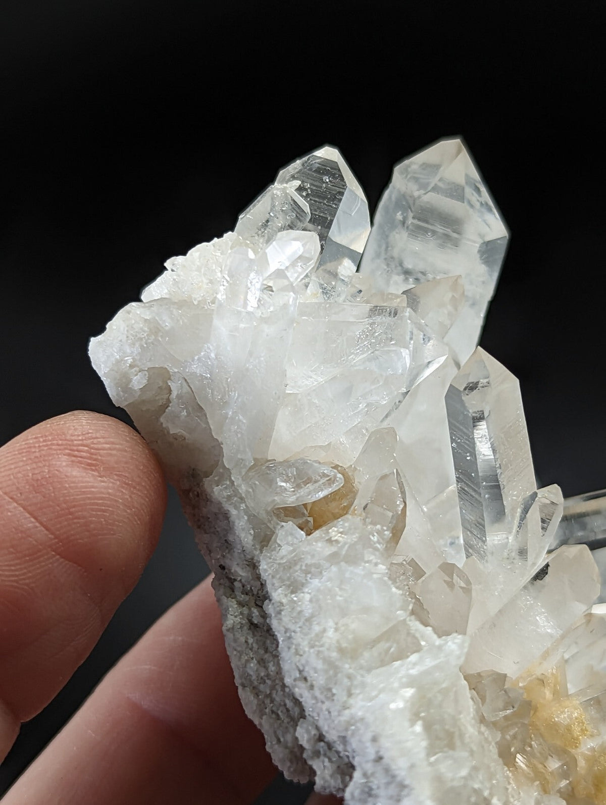 A cluster of clear, translucent quartz crystals with sharp facets and a white matrix base.
