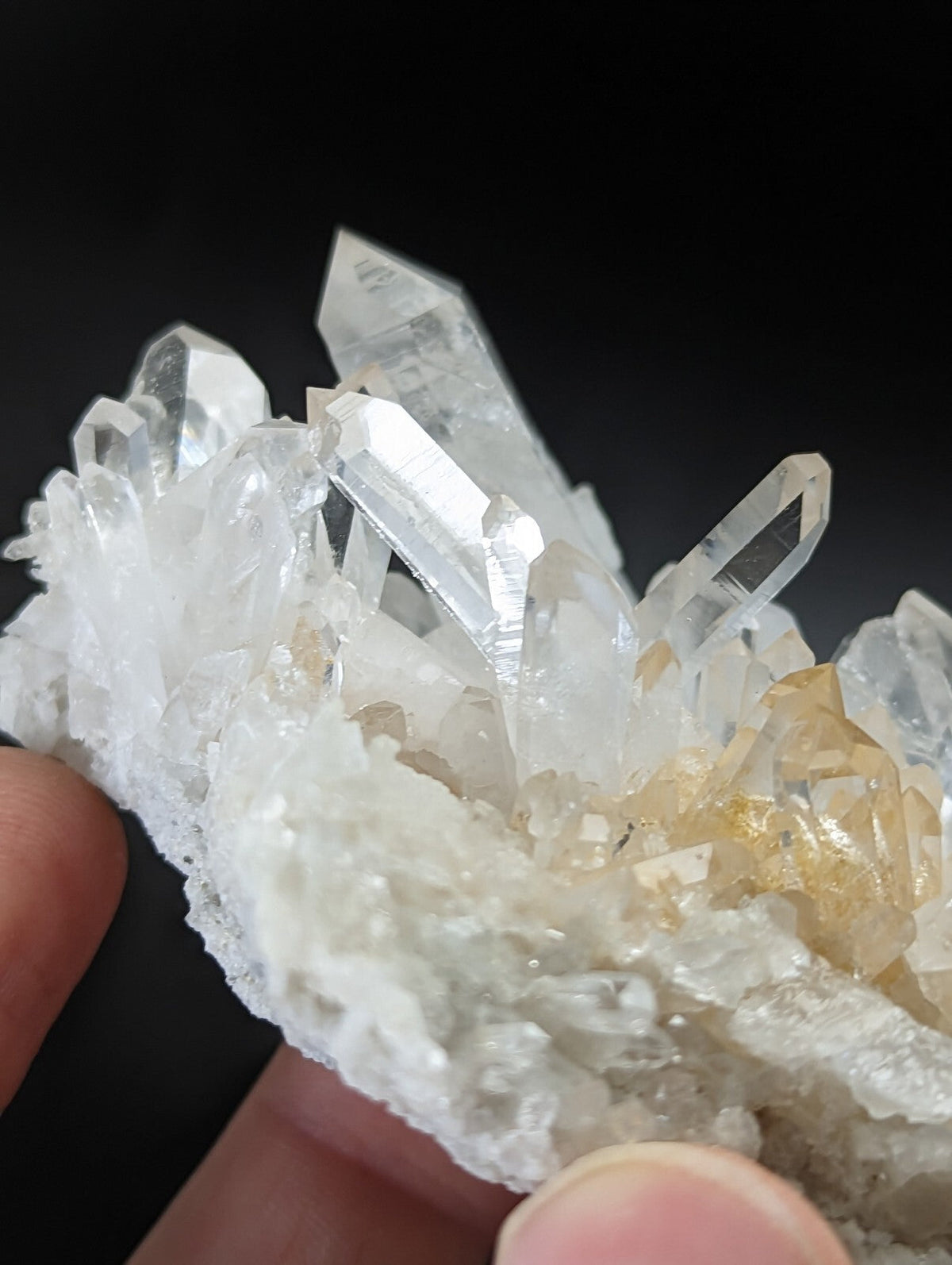 A cluster of clear, translucent quartz crystals with some exhibiting a subtle golden hue.