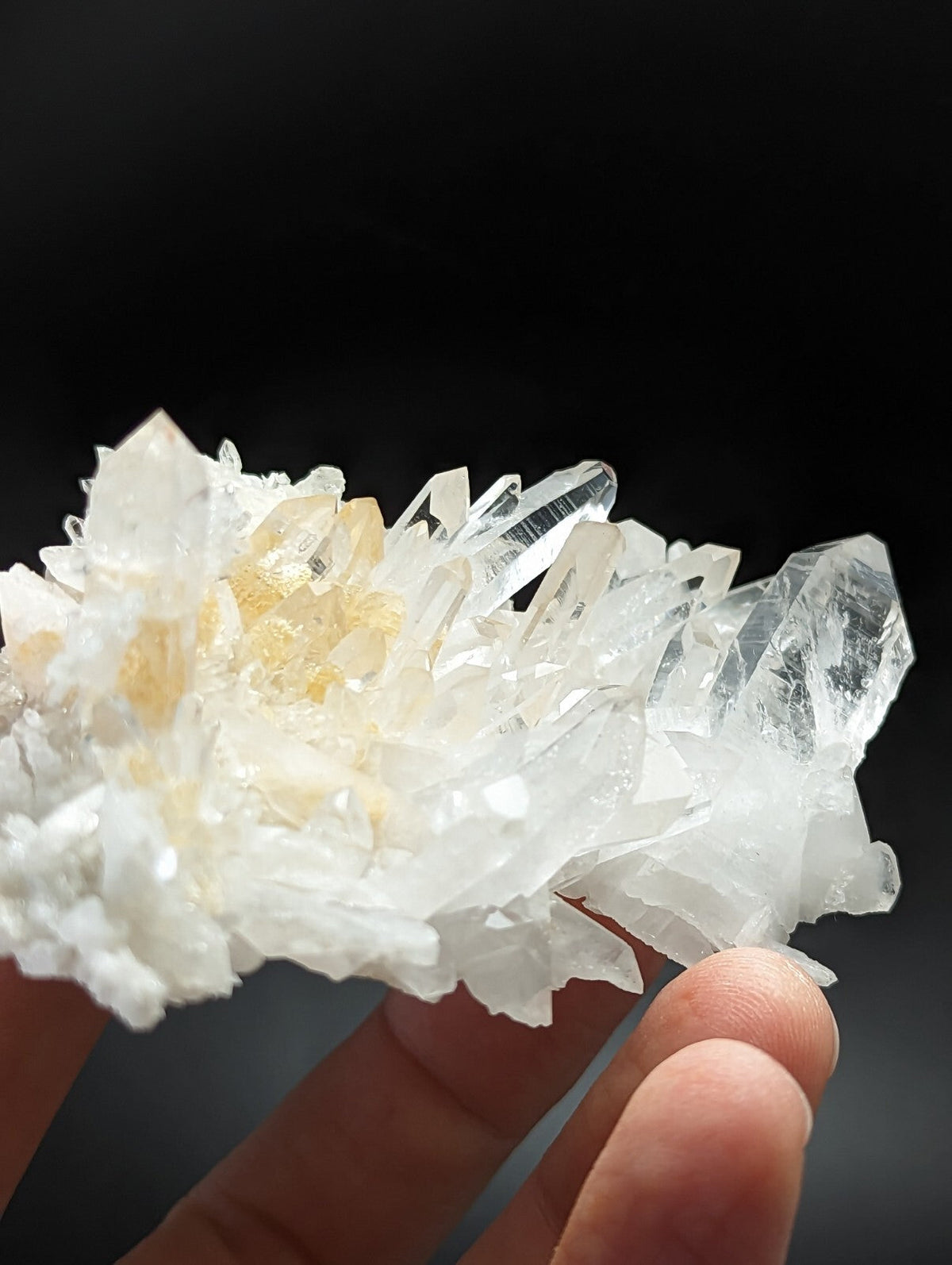 A translucent white quartz crystal cluster with sharp, pointed facets and subtle golden-yellow inclusions.