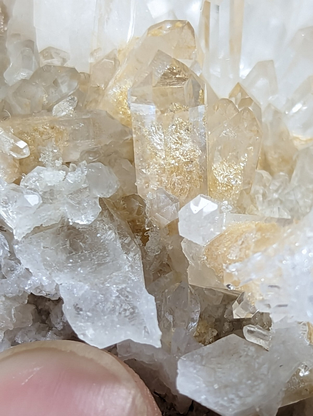 A cluster of translucent, golden-hued quartz crystals with sharp, faceted edges and a crystalline structure.