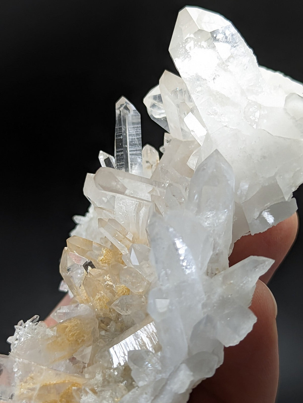 A translucent white quartz crystal cluster with sharp, faceted points and subtle golden-yellow inclusions.