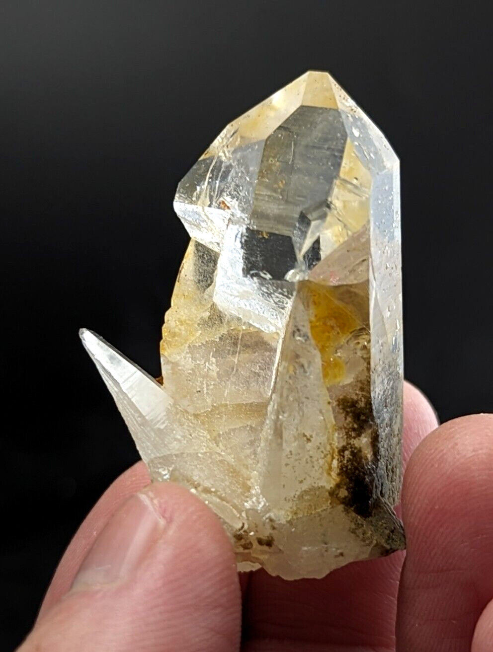 A translucent yellowish quartz crystal with a pointed, faceted top and natural inclusions.